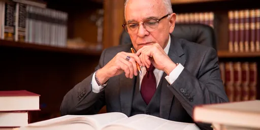 Manos de un consultor revisando contratos y documentos legales sobre un escritorio de madera.